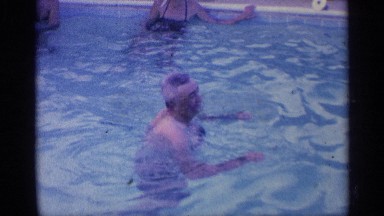 1959: a man swimming the swimming pool near to another men and women wall steps