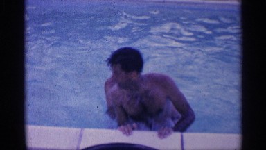 1959: two men are playing with each other in the pool trying to knock the other