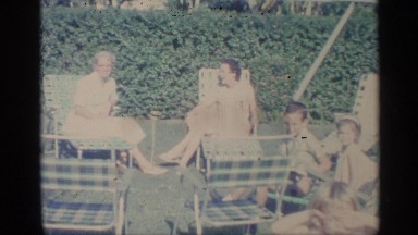 1959: family of women and children enjoying a picnic on a lawn outside with lawn
