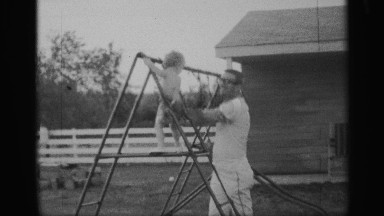 1959: a man and his boy kid playing at the playground at the iron line it near