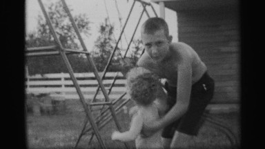 1959: a teenager helping his younger brother to climb on a scaling set NEW YORK