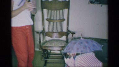 1959: kids playing in home, enjoying around the chair, playing with umbrella