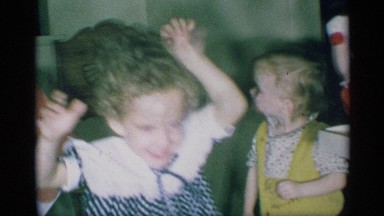 1959: a little girl with curly hair dances around while her brother watches