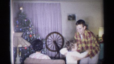 1959: a boy raises a toddler on and both dance together on front an adult