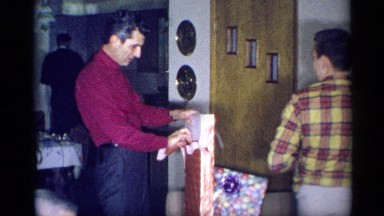 1959: a young man unwrapping the gift parcel before his friend opens another box