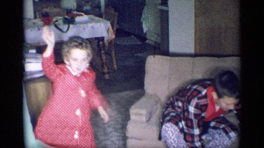 1959: A young girl stands waving at the camera while a boy in a bathrobe