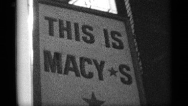 1959: a camera pans down a large sign for macy's department store