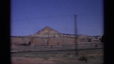 1959: footage of mountains next to a highway taken from a moving vehicle.