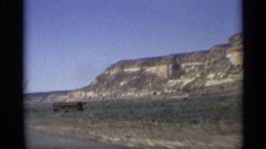 1959: a car slow drive to watch the natural view distance mountain come to near