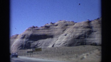 1959: drive in a car slow near to big mountain only stone near name sign board
