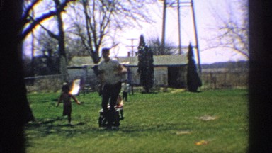 1959: a man and two children are played in the park he carry the child and run