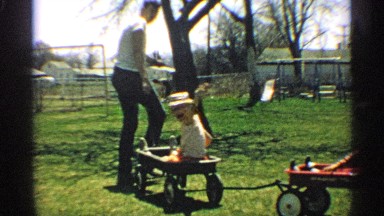 1959: a woman pulls two wagons with children having fun in play ground