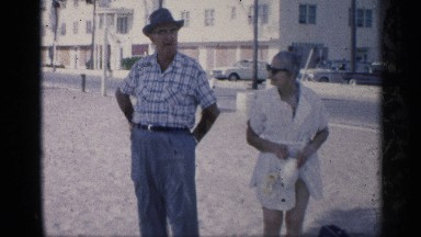1959: men and women standing on a windy day over sand , waving hand. CALIFORNIA