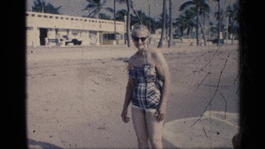 1959: elderly woman on the beach being approached by a younger boy with a man