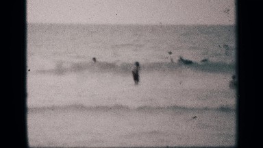1959: person at beach stands facing ocean and lifts both arms to wave CALIFORNIA