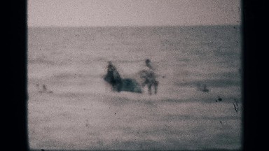 1959: some peoples are playing on the beach on the water running to the air