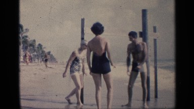 1959: people spending time together in beach with family and playing in tides