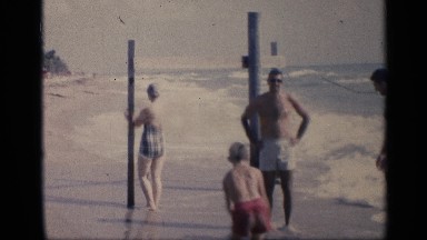 1959: some people and a kid are playing and taking bath at the ocean
