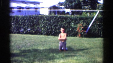 1959: the boy was kneel down in the garden and laugh very much
