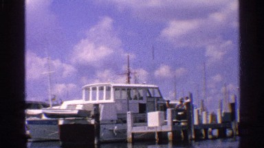1959: boat is departing and is have one last view of the boats on the dock