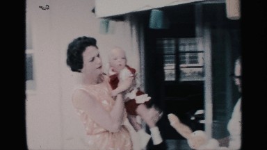 1959: well-dressed woman accepts baby girl from older woman in house