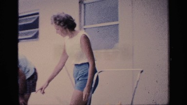 1959: woman walks and crouches by toddler girl with parents and a white dog