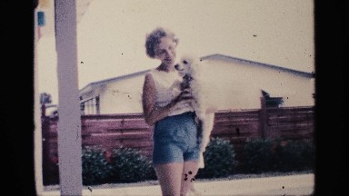 1959: women playing with her pet dog in white color,near a pool area in house