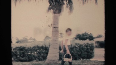 1959: teenage boy with a basket walks around a palm tree and finds an easter egg