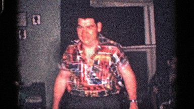 1959: A Man Walks to Family as Members Smile, Including a Small Boy Answering