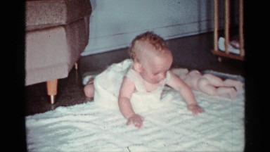 1959: a little kid trying to move at the bed and a toy near to the kid