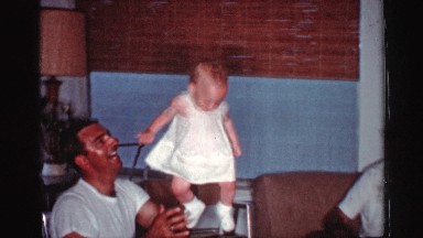 1959: a men handle a baby in one hand and the baby is stand and sit on the man
