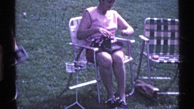 1969: a lady is sitting on the chair at outside and watching the river and boat