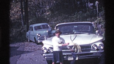 1969: a little girl standing in front of car and dancing with cloth ropes