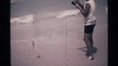 1973: a young person stands at the edge of the ocean while holding a recently