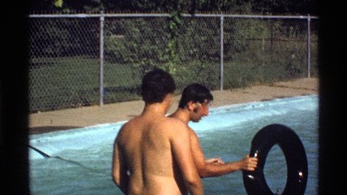 1978: two friends play inside the local pool with a floating round black tire