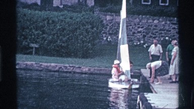1969: some people standing on the bank of the pool with a flag on the boat OHIO
