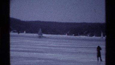 1969: family standing on iced over water as a boat slides by in the background