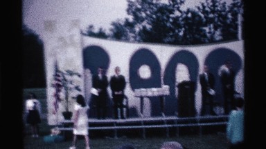 1969: some peoples are standing on the stage they wear black coat and others sit