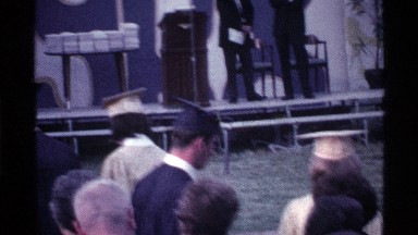 1969: two men in dark suits stand on platform during graduation procession OHIO