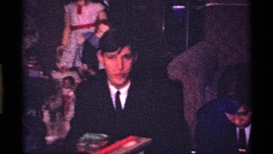 1969: a big party boys and girls sit in the furniture bench top food and drink