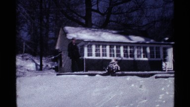 1969: two children sits on a sled on front a home and slide on the slope