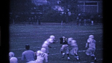 1969: Players Rush Man Running and Carrying Football on Football Field. Ohio