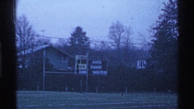1969: partially empty bleacher at dusk while people exiting the football field