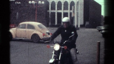 1976: Stationary Motorist in Parking Lot with Cars in Front of Fallout Shelter