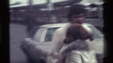 1976: a smiling lady walks up to and hugs a man standing near a car KENTUCKY