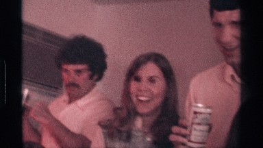 1976: a large group of people gathered in a small room inside of a home