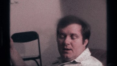 1976: the man sit and talking to someone he had drinks in his hand its look like