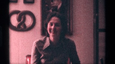 1976: one woman speak to other person and smile back to the wall picture