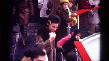 1970: a lady and her children peek through a fence then at the camera NEW YORK