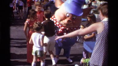 1974: milling people, accosting costumed individual, on sunny day. ORLANDO